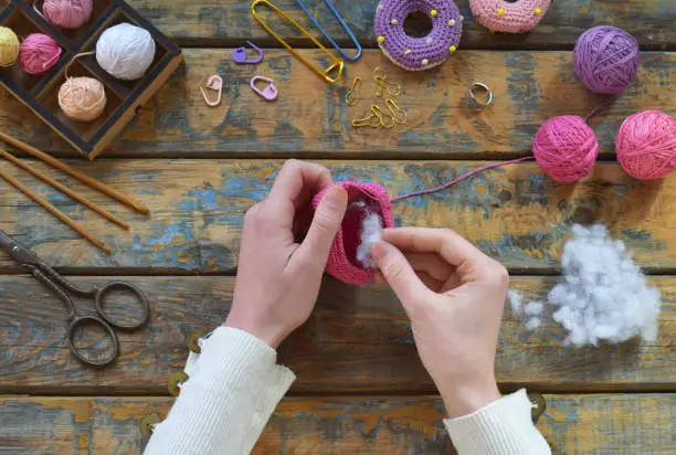 Mains de femme tricotant un amigurumi en crochet avec des accessoires