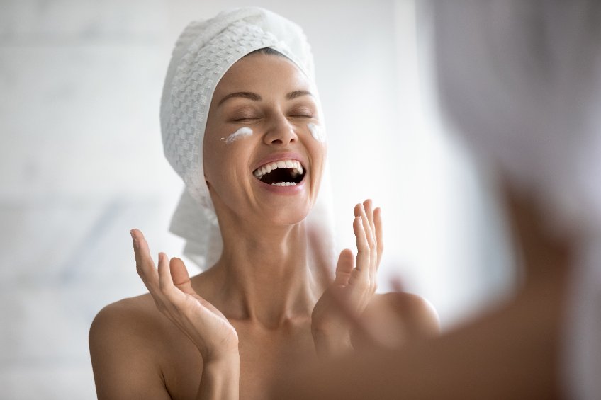 Femme venant de prendre sa douche et s'appliquant de la crème sur le visage