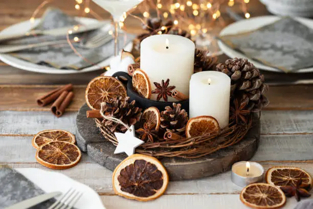Décoration rustique de Noël dans un coupe avec des bougies, de la cannelle et de l'orange séchée