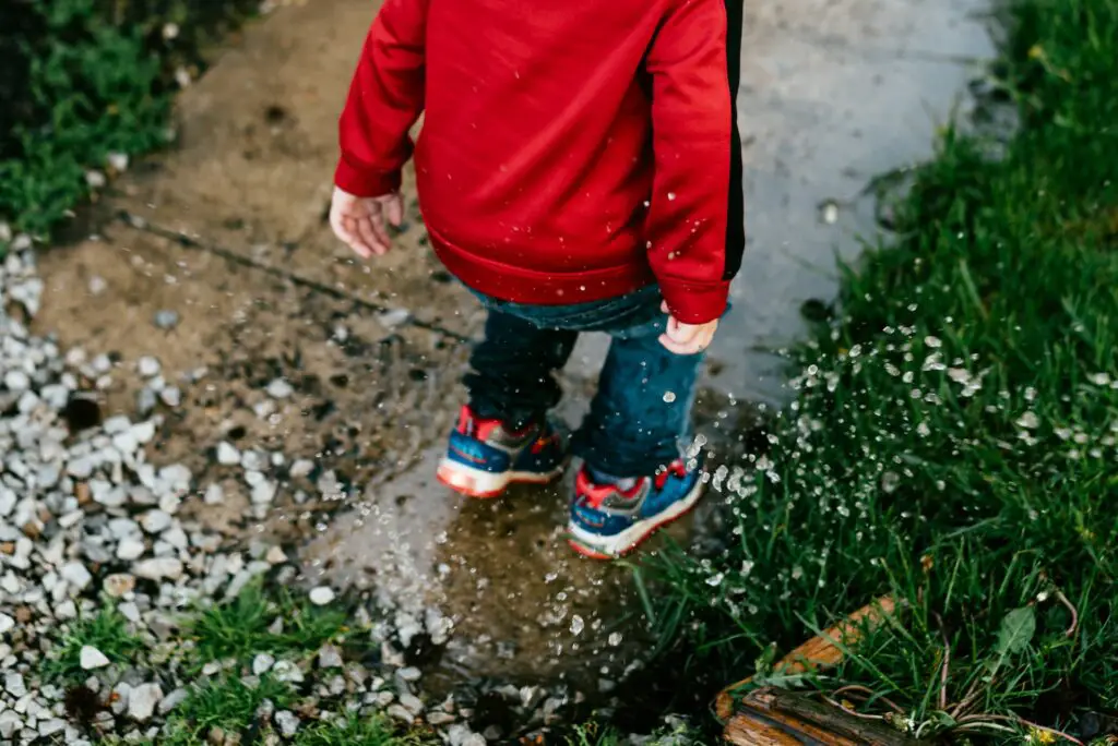 Enfant sautant dans une flaque d'eau par temps de pluie