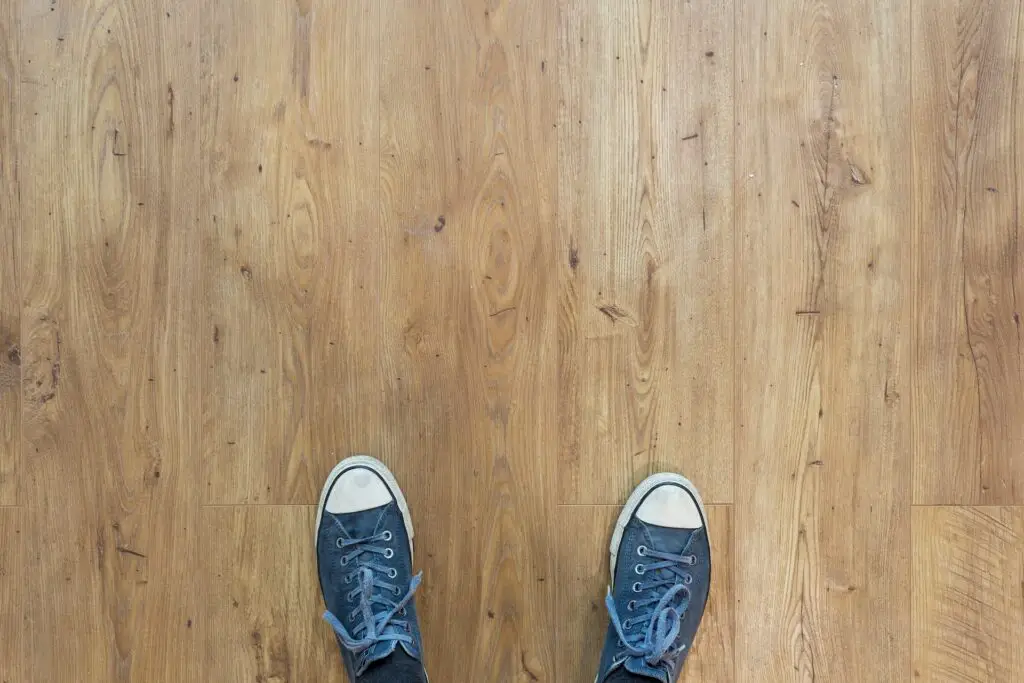 Photographie des pieds d'une personne sur un parquet propre